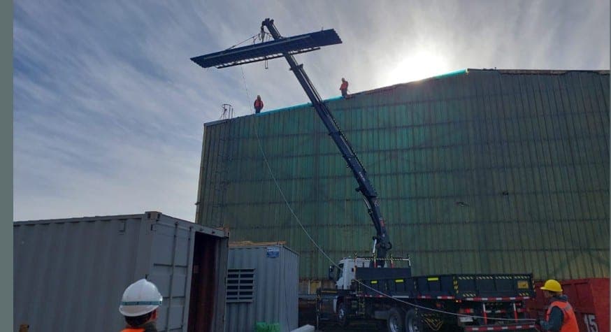 Montaje de panel en cubierta industrial con grúa
